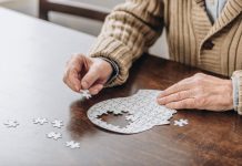 Een oudere man maakt een legpuzzel van een hoofd waarin de stukken van de hersenen nog ontbreken