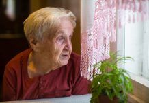 Oudere vrouw kijkt uit raam