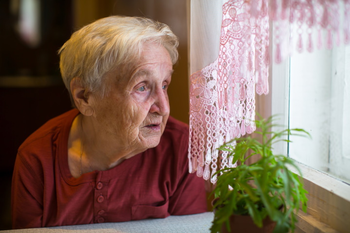Oudere vrouw kijkt uit raam